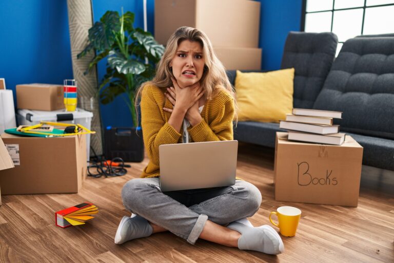 Young woman sitting on the floor at new home using laptop.